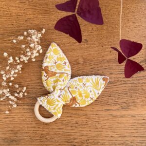 hochet de dentition en bois naturel et éponge de bambou blanche avec un tissu coton blanc avec des singes et des feuillages jaune