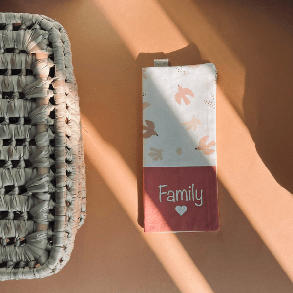 protège livret de famille avec un tissu hirondelles roses sur fond blanc et un tissu uni saumon sur lequel est écrit family avec un coeur