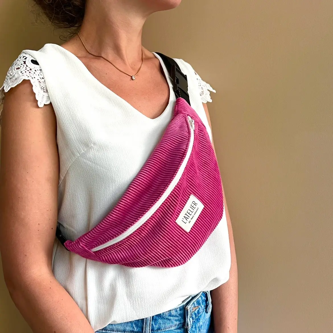 sac banane en velours côtelé rose fuchsia avec fermeture éclair couleur ivoire. Anse réglable noire à paillettes dorées. Photo portée. Contact – L’Atelier de Nos Envies | Créations artisanales faites main