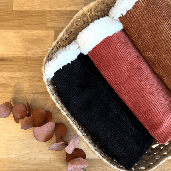 Trois tours de cou chauds dans une panière. Tissus extérieurs en velours côtelé noir, rouille et camel. Tissu intérieur en sherpa ivoire.