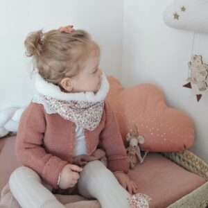 Tour de cou chaud porté par une petite fille. Tissu extérieur à fleurs dans les tons marsala et tissu intérieur en sherpa couleur ivoire.